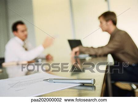 Stock Image - Businessmen working together in office space, blurred.. Fotosearch