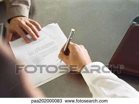Stock Image - Businessperson signing paper.. Fotosearch
