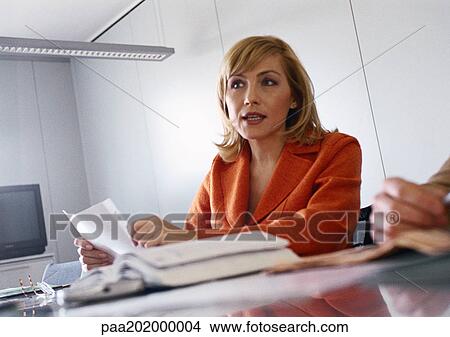 Businesswoman sitting at table with open book. View Large Photo Image Picture - Businesswoman sitting at table with open book.. Fotosearch