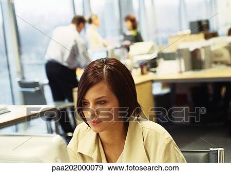 Businesswoman working on computer, business people working in background. View Large Photo Image Stock Photo - Businesswoman working on computer, business people working in background.. Fotosearch
