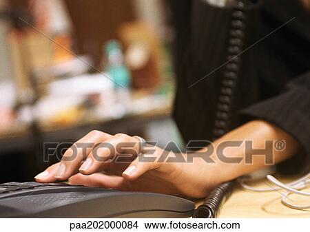 Picture - Businesswoman's hand dialing phone, close up.. Fotosearch