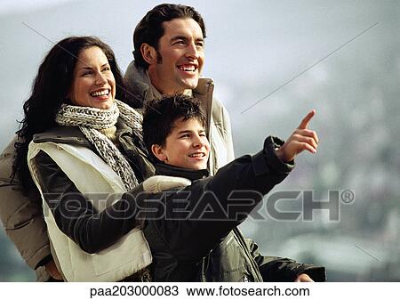 Stock Image - Adult man and woman with boy, warmly dressed, boy pointing and adults looking in direction that boy is pointing, waist up. Fotosearch