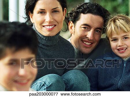 Adult man and woman with little girl, smiling, in background, little boy blurred in foreground View Large Photo Image Stock Photo - Adult man and woman with little girl, smiling, in background, little boy blurred in foreground. Fotosearch
