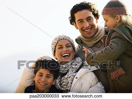 Stock Image - Adult man and woman with two children, smiling, warmly dressed, oustside, portrait.. Fotosearch
