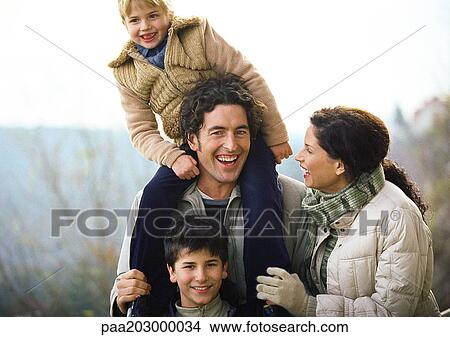 Adult woman and adult man standing outside with two children, little girl on man's shoulders, portrait View Large Photo Image Picture - Adult woman and adult man standing outside with two children, little girl on man's shoulders, portrait. Fotosearch