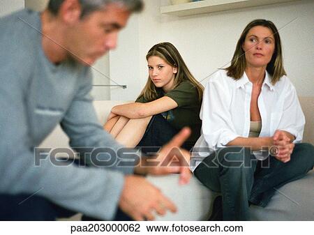 Stock Image - Family, man blurred in foreground, mother and daughter in background, portrait.. Fotosearch