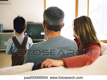 Family sitting together, watching TV. View Large Photo Image Picture - Family sitting together, watching TV.. Fotosearch