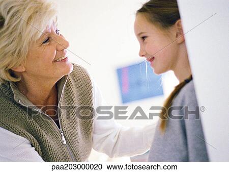 Stock Image - Grandmother and granddaughter looking at each other, close up.. Fotosearch