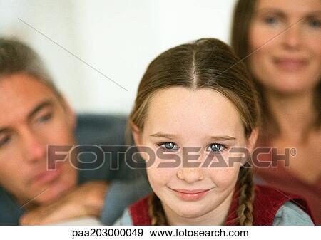 Little girl with pigtails smiling, adult man and woman in background, close-up, portrait View Large Photo Image Stock Photo - Little girl with pigtails smiling, adult man and woman in background, close-up, portrait. Fotosearch