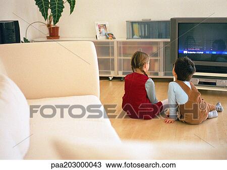 Lttle boy and girl sitting together on parquet floor looking at tv, rear view View Large Photo Image Stock Image - Lttle boy and girl sitting together on parquet floor looking at tv, rear view. Fotosearch