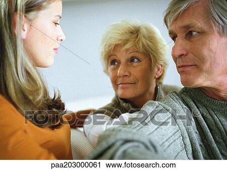 Stock Image - Teenage girl, side view, facing two senior adults, head and shoulders, close-up. Fotosearch