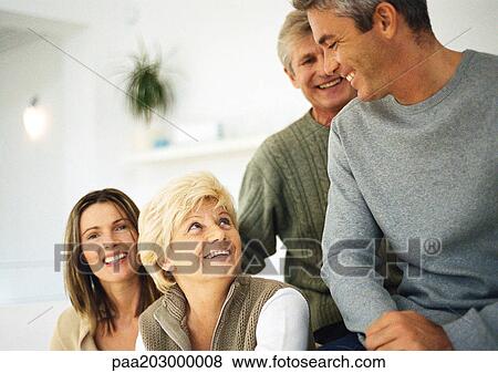 Two women smiling, head and shoulders, one looking up, two men, waist up, in living room setting View Large Photo Image Stock Photo - Two women smiling, head and shoulders, one looking up, two men, waist up, in living room setting. Fotosearch