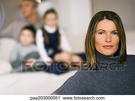 Woman in foreground, head and shoulders, man and two children blurred in background, on sofa View Large Photo Image Stock Image - Woman in foreground, head and shoulders, man and two children blurred in background, on sofa. Fotosearch
