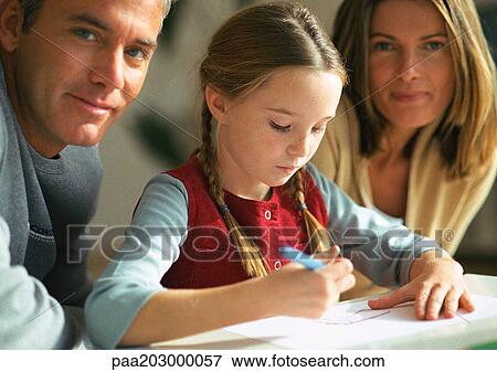 Young girl looking down at table, drawing, between adult man and woman, looking at camera, close-up View Large Photo Image Stock Photo - Young girl looking down at table, drawing, between adult man and woman, looking at camera, close-up. Fotosearch