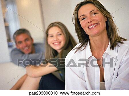 Stock Image - Young woman and man smiling and looking in same direction, woman smiling in foreground, head and shoulders. Fotosearch