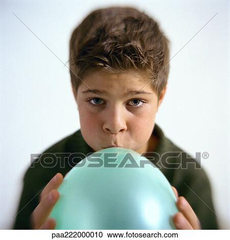 Stock Image - Boy blowing up balloon, portrait. Fotosearch