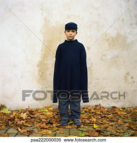 Boy standing among autumn leaves, wearing oversized sweater View Large Photo Image Stock Photography - Boy standing among autumn leaves, wearing oversized sweater. Fotosearch