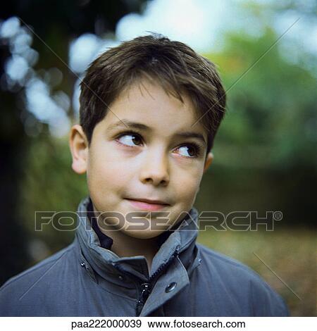 Stock Photo - Boy wearing coat outside, looking away, portrait. Fotosearch