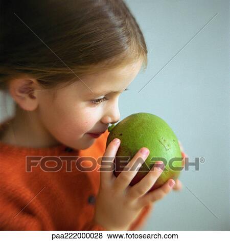 Girl smelling fruit, head and shoulders, close-up View Large Photo Image Stock Photo - Girl smelling fruit, head and shoulders, close-up. Fotosearch