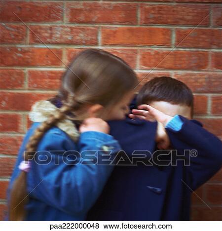 Girl trying to kiss boy, boy covering face with arms, blurred View Large Photo Image Stock Photo - Girl trying to kiss boy, boy covering face with arms, blurred. Fotosearch