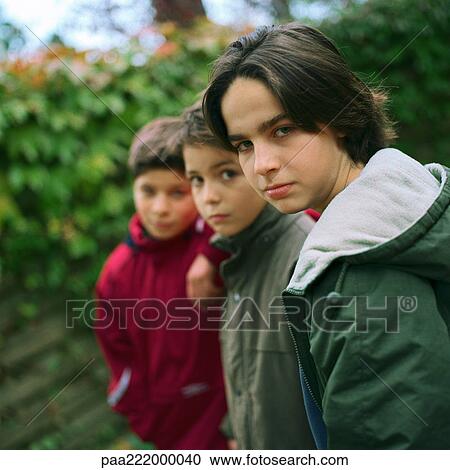 Stock Image - Three boys looking into camera, outside. Fotosearch