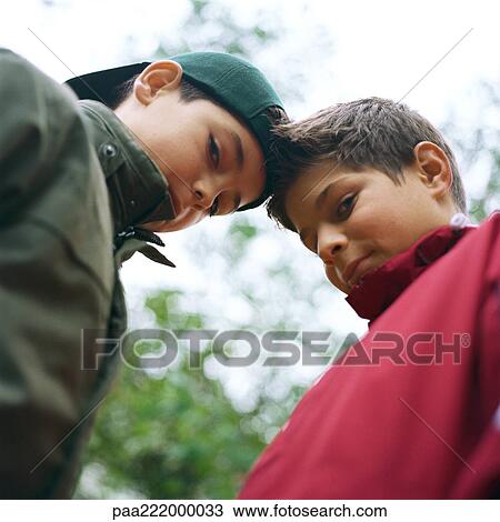 Two boys face to face looking at camera, low angle view View Large Photo Image Stock Image - Two boys face to face looking at camera, low angle view. Fotosearch