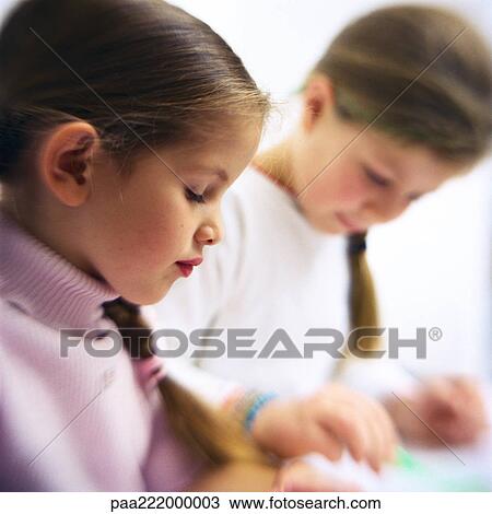 Stock Image - Two girls sitting at table, side view. Fotosearch