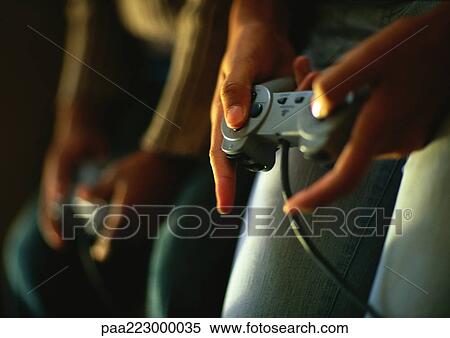 Stock Photography - Hands of children playing video game, close up.. Fotosearch