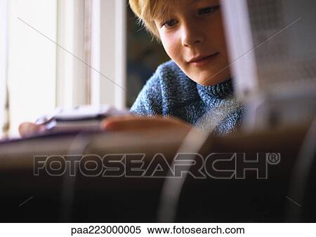 Young boy looking at video game, close up, computer and desk blurred in foreground View Large Photo Image Stock Photography - Young boy looking at video game, close up, computer and desk blurred in foreground. Fotosearch