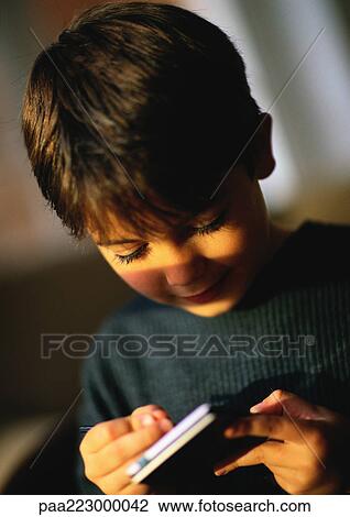 Young boy playing with hand held personal assistant, close up. View Large Photo Image Stock Image - Young boy playing with hand held personal assistant, close up.. Fotosearch