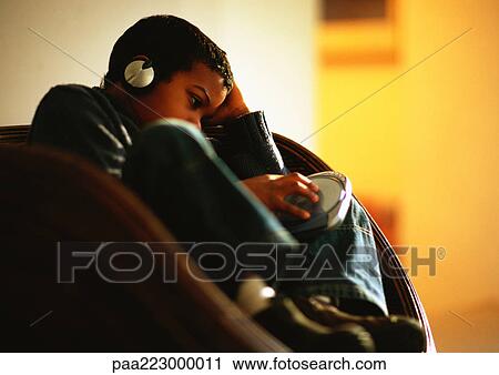 Young boy sitting in chair listening to music with headphones. View Large Photo Image Stock Image - Young boy sitting in chair listening to music with headphones.. Fotosearch