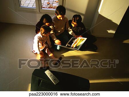 Young boys and girls sitting on floor looking at a book, high angle view View Large Photo Image Stock Photograph - Young boys and girls sitting on floor looking at a book, high angle view. Fotosearch