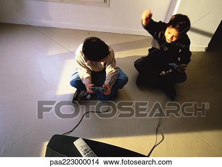 Young boys sitting on floor playing video game, high angle view View Large Photo Image Picture - Young boys sitting on floor playing video game, high angle view. Fotosearch