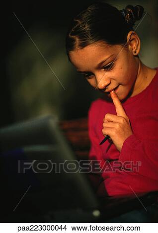 Young girl looking down at computer, close up. View Large Photo Image Picture - Young girl looking down at computer, close up.. Fotosearch