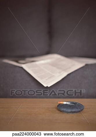 Ashtray on table next to couch with newspaper View Large Photo Image Stock Image - Ashtray on table next to couch with newspaper. Fotosearch