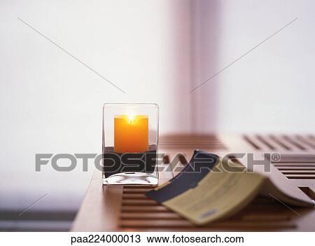 Stock Image - Candle and open book on table. Fotosearch