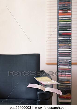 Chair with open CD case and booklet on arm, CD rack nearby. View Large Photo Image Stock Image - Chair with open CD case and booklet on arm, CD rack nearby.. Fotosearch