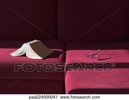Stock Photo - Glasses and open book on couch.. Fotosearch