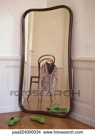 Mirror reflecting chair with blouse hanging from it and pair of shoes on floor View Large Photo Image Picture - Mirror reflecting chair with blouse hanging from it and pair of shoes on floor. Fotosearch