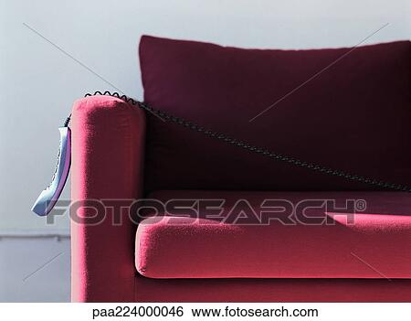Phone hanging off of couch arm. View Large Photo Image Stock Photograph - Phone hanging off of couch arm.. Fotosearch