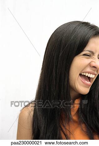 Stock Image - Woman laughing, eyes shut, partial view portrait.. Fotosearch