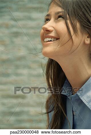 Stock Photo - Woman smiling, looking up, portrait.. Fotosearch
