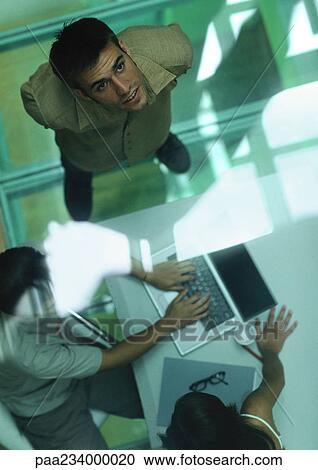 Group of people working around laptop, high angle view through glass View Large Photo Image Stock Image - Group of people working around laptop, high angle view through glass. Fotosearch