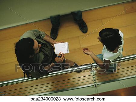 Stock Photo - Man and woman leaning against rail, talking, view from above.. Fotosearch