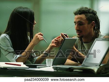 Man and woman sitting with laptop computers, talking View Large Photo Image Stock Photo - Man and woman sitting with laptop computers, talking. Fotosearch