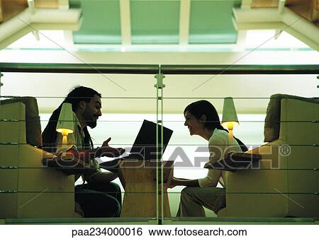 Stock Photograph - Man sitting and talking with woman, side view. Fotosearch