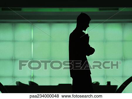 Stock Photo - Man standing in front of windows, silhouette.. Fotosearch