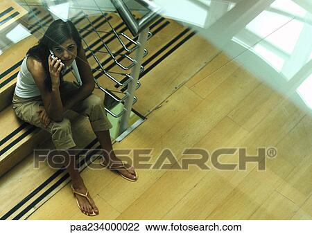 Woman sitting on stairs talking on cell phone, view from above. View Large Photo Image Stock Image - Woman sitting on stairs talking on cell phone, view from above.. Fotosearch