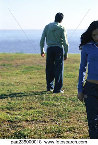 Man and woman standing on grass by water facing different directions. View Large Photo Image Stock Photo - Man and woman standing on grass by water facing different directions.. Fotosearch