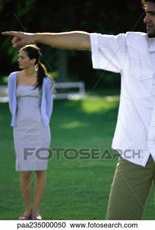 Man pointing, woman looking in background View Large Photo Image Stock Image - Man pointing, woman looking in background. Fotosearch